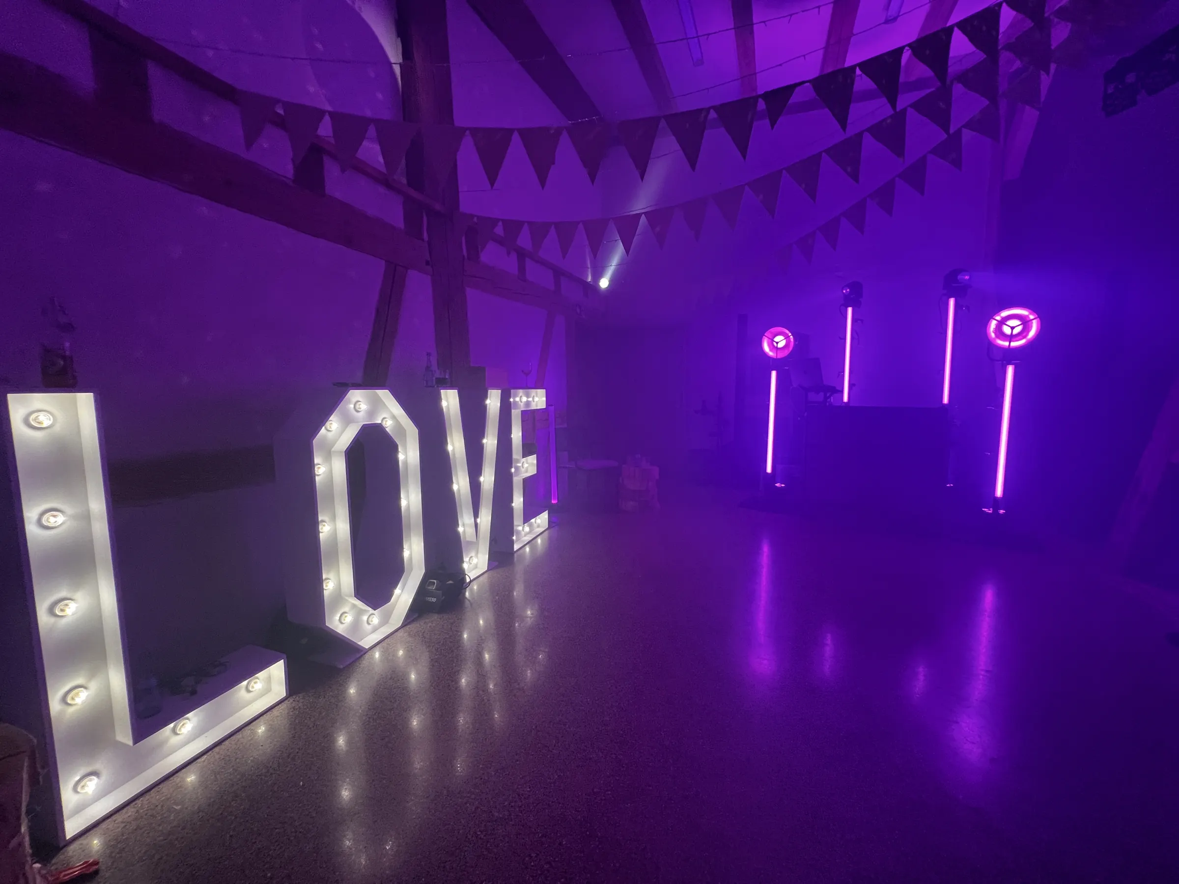 Vorbereitete Tanzfläche mit Love-Schriftzug und DJ-Setup in violettem Licht